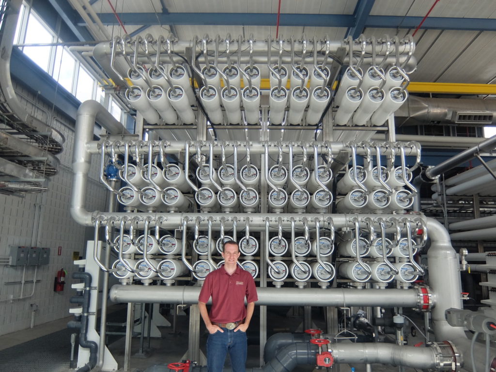 Texan standing in front of a large array of pipes and tubes.